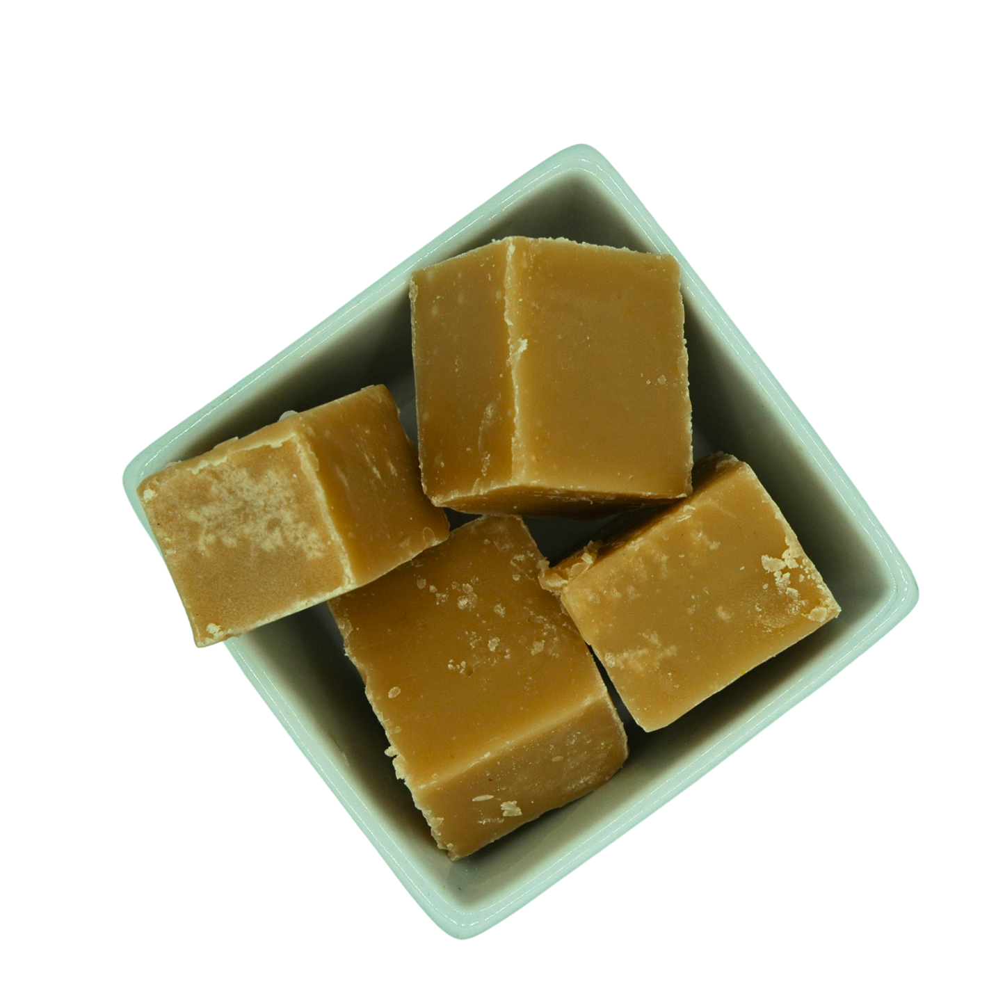 Cubes of caramel fudge in a white bowl on a white background
