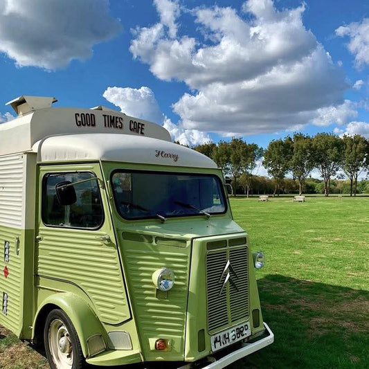 Green street food van good times cafe on a sunny day in a field 