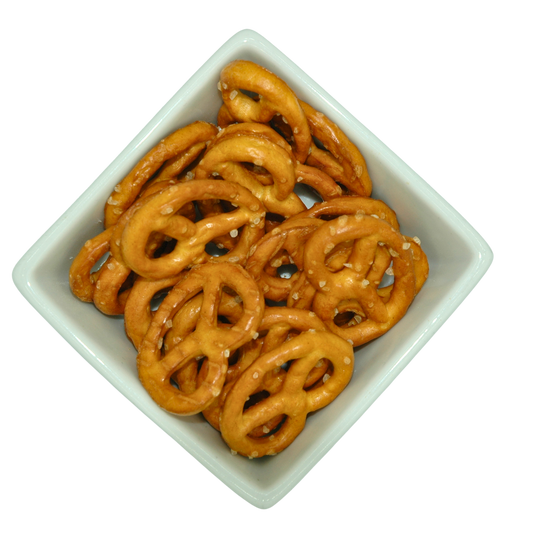 Pretzels covered in large salt crystals n a square white bowl on a white background