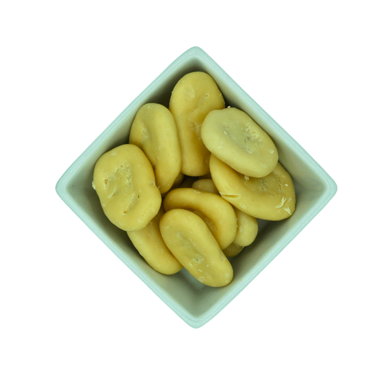 White ceramic bowl filled with yellow yoghurt coated banana chips on a white background