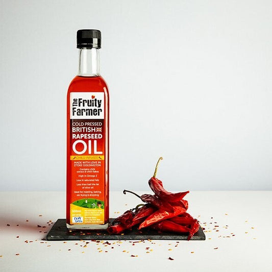 Bottle of 'The Fruity Farmer' rapeseed oil with dried red peppers on a white background