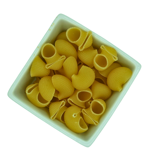 Yellow shell pasta in a white bowl on a white background