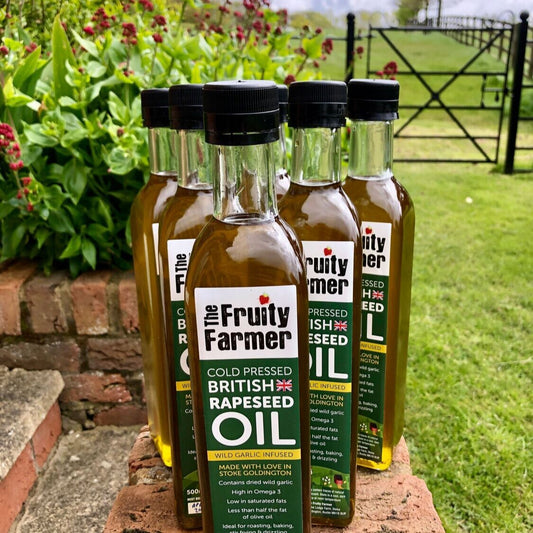 Bottles of 'The Fruity Farmer' oil on a brick ledge with a garden background