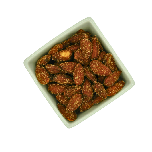 Square white bowl filled with roasted almonds on a white background