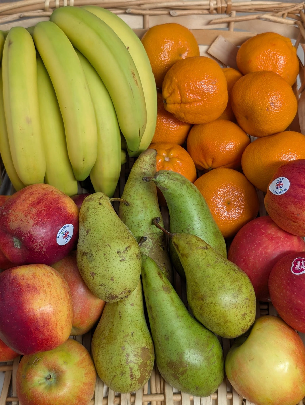 A fruit box containing a selection of Bananas, apples, pears and easy peelers