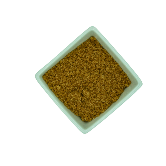 Square white dish filled with brown granular sugar on a white background