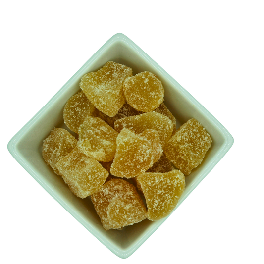 White bowl filled with crystalised ginger chuncks on a white background