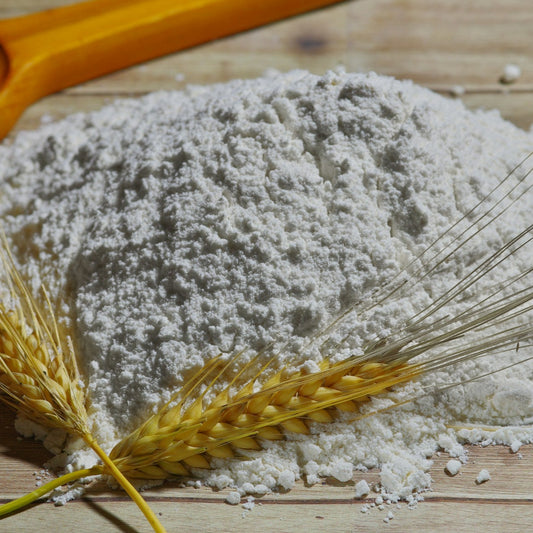 Wheat flour on a wooden surface with wheat stalks