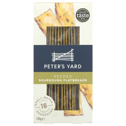 A package of Peter's Yard Seeded Sourdough Flatbreads, showing the front of the box with a dark blue band, white text, and illustrations of flatbreads on a white background.
