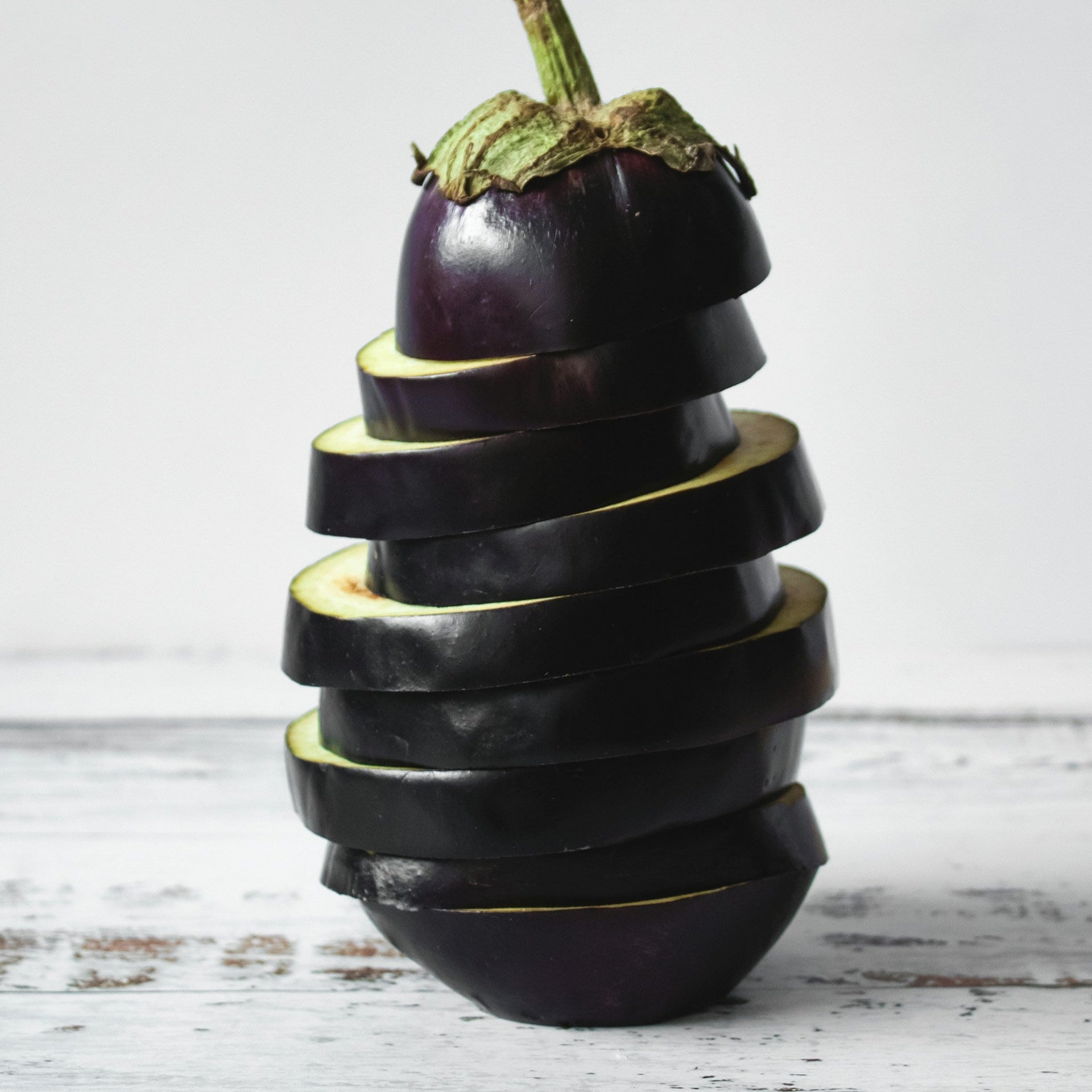 Stacked eggplant on a white wooden surface